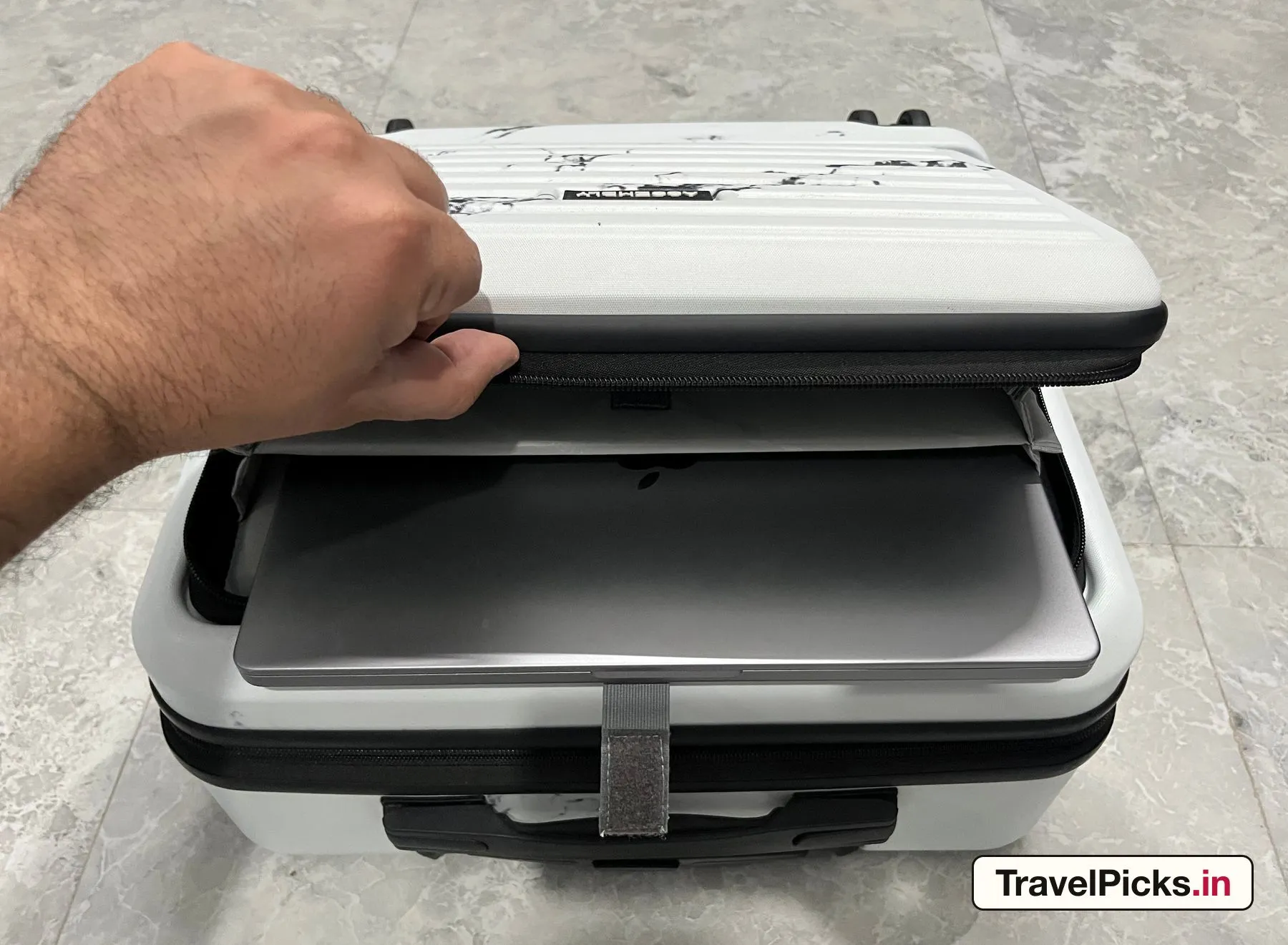 A silver 14-inch laptop lying flat inside the case's front compartment, the panel held open.
