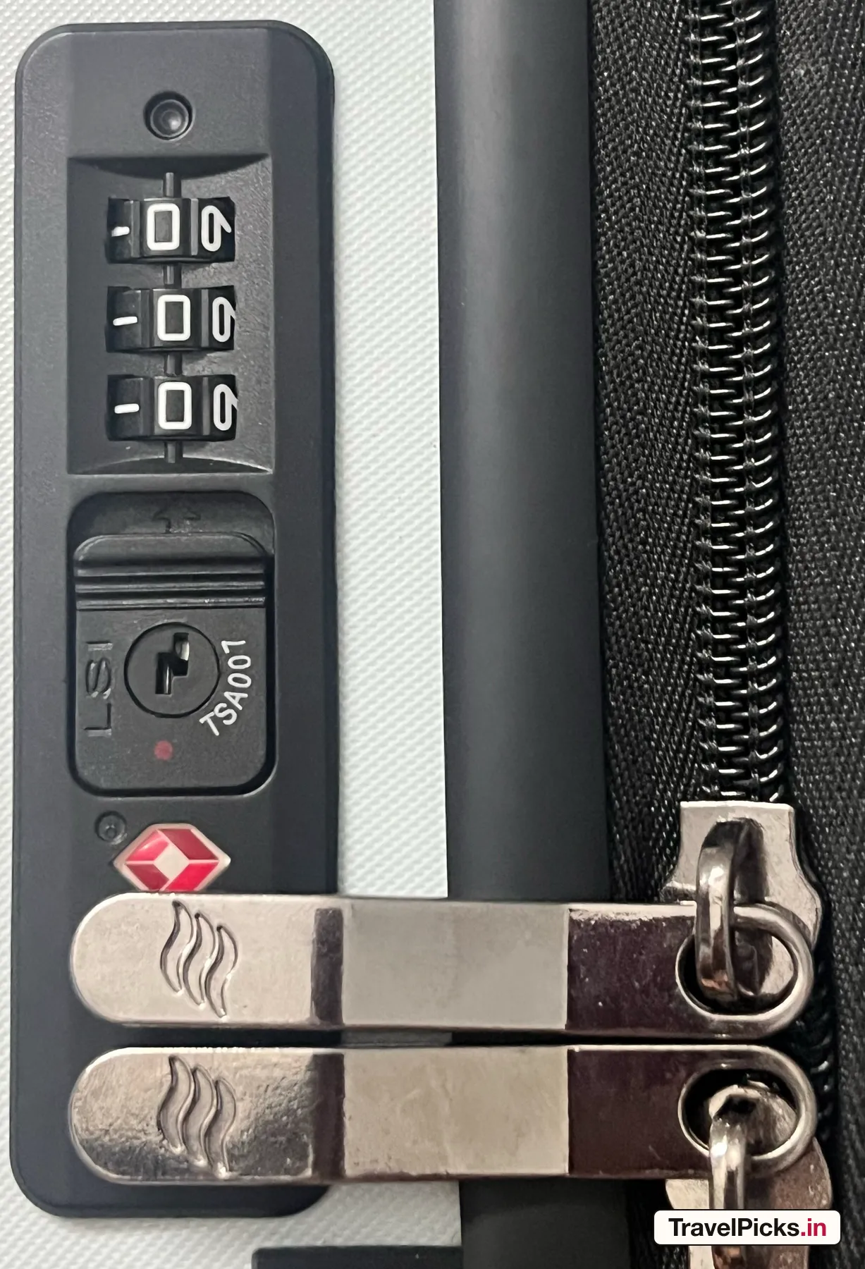 The same lock closed, with both metal zip pullers held under the shackle beside the main zip chain.