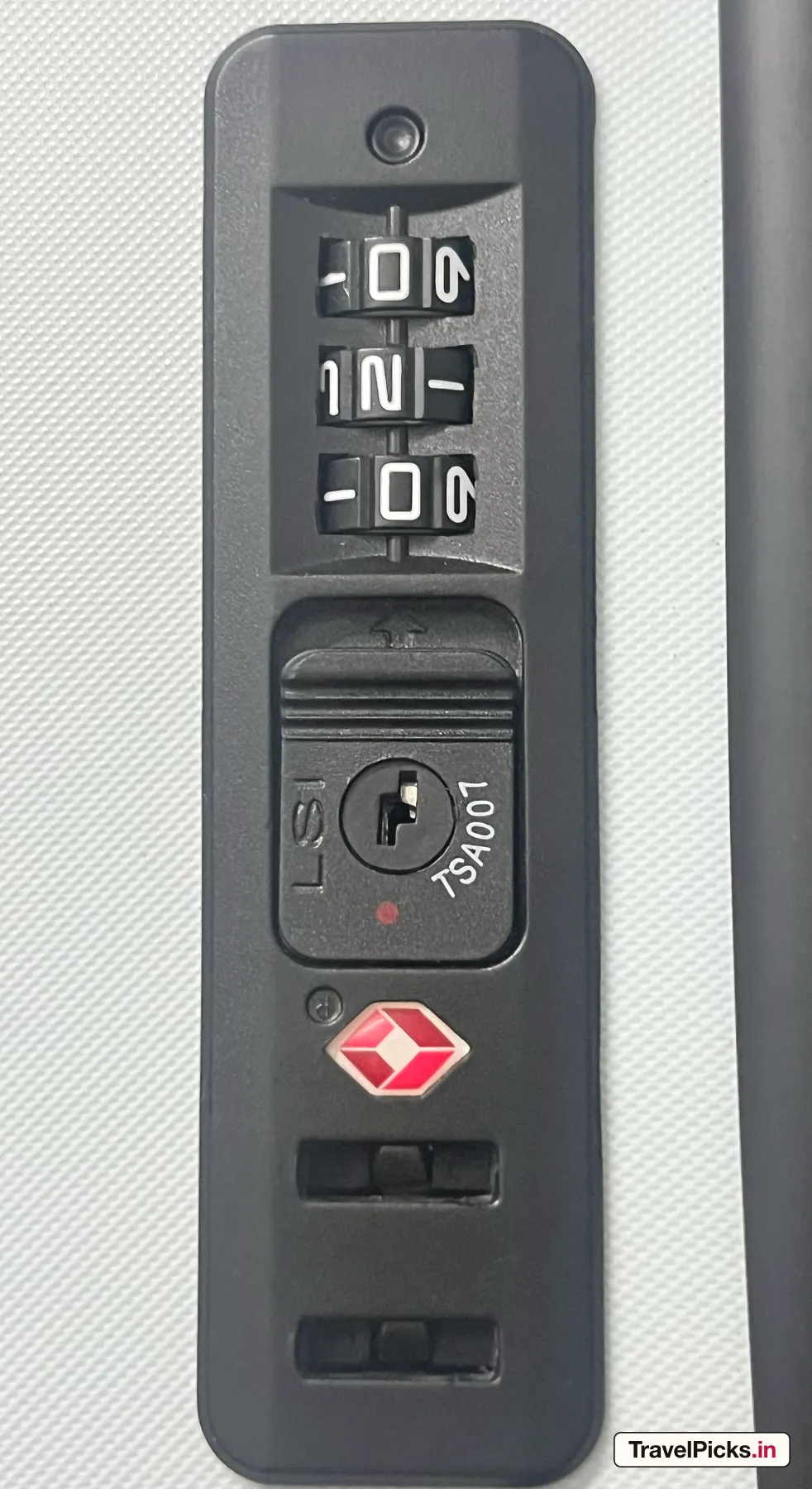 The lock plate on the white shell: three dials, a keyway stamped TSA007, and two empty shackle slots below it.