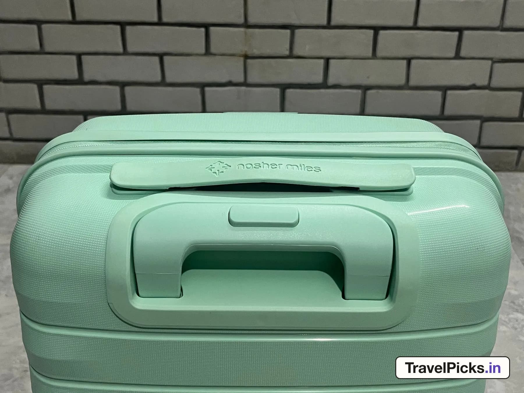 The top of the case seen from above, with the trolley grip sitting flush in a recessed well and a flat carry handle embossed with the brand name.
